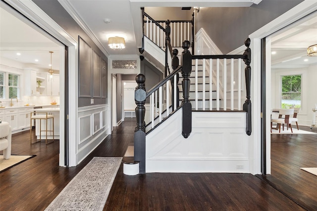 53 Jay St, Katonah, NY 10536 - stairs with a decorative wall, wood finished floors, crown molding, and a chandelier