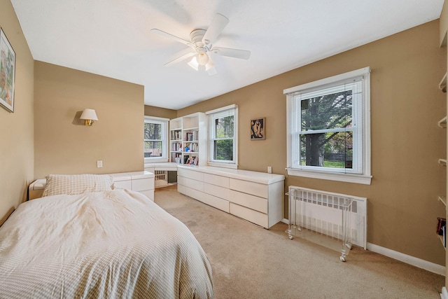 bedroom featuring ceiling fan, radiator heating unit, light colored carpet, and baseboards