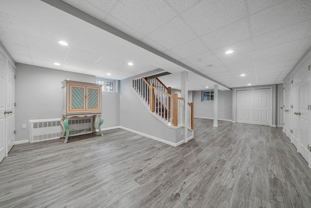 basement featuring baseboards, wood finished floors, stairs, and a drop ceiling
