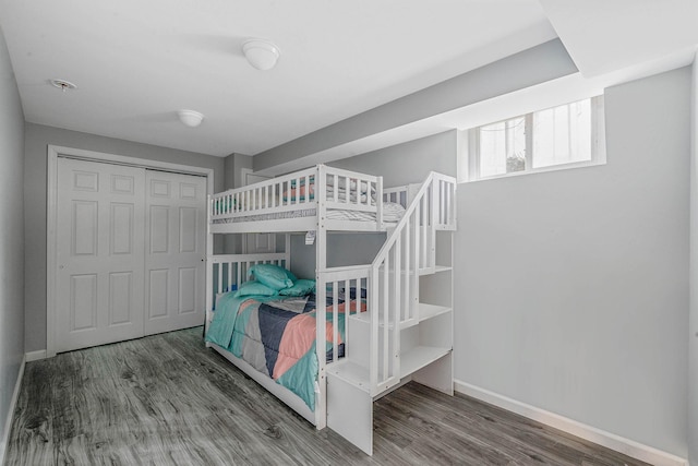 bedroom featuring baseboards, wood finished floors, and a closet