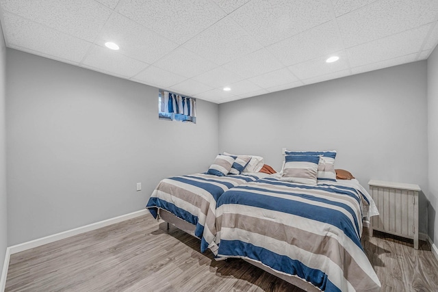 bedroom featuring wood finished floors, baseboards, recessed lighting, and radiator