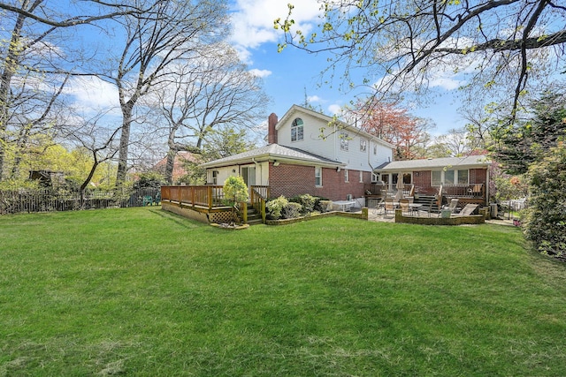 rear view of property featuring a patio area, a yard, a fenced backyard, brick siding, and a deck