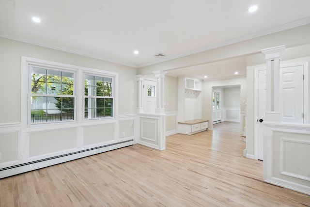 unfurnished room featuring ornate columns, a baseboard heating unit, light wood-style flooring, and a decorative wall