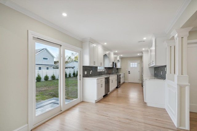 kitchen with light wood-style floors, light countertops, appliances with stainless steel finishes, and tasteful backsplash