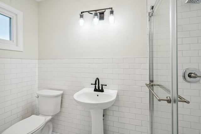 full bathroom with toilet, tile walls, a shower stall, and a wainscoted wall