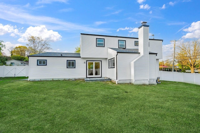 back of property with a fenced backyard, french doors, a yard, and a chimney