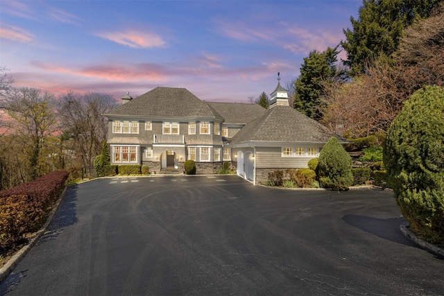 french provincial home featuring a chimney, aphalt driveway, a shingled roof, and stone siding