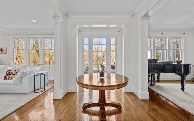 entrance foyer with baseboards, wood finished floors, and ornate columns