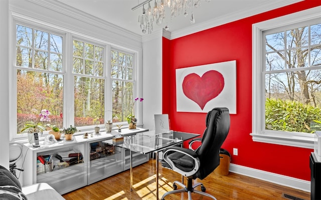 home office with an inviting chandelier, visible vents, baseboards, ornamental molding, and wood finished floors