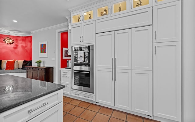 kitchen with glass insert cabinets, light tile patterned floors, double oven, ornamental molding, and white cabinetry
