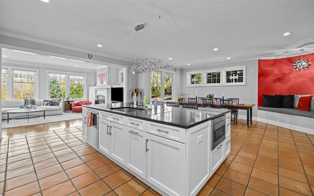 kitchen with recessed lighting, open floor plan, crown molding, and a sink