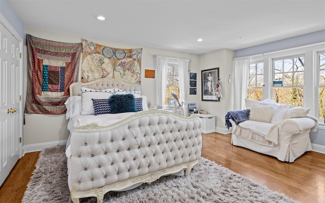 bedroom with multiple windows, wood finished floors, and baseboards