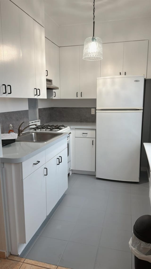 kitchen featuring white cabinetry, a sink, light countertops, freestanding refrigerator, and under cabinet range hood
