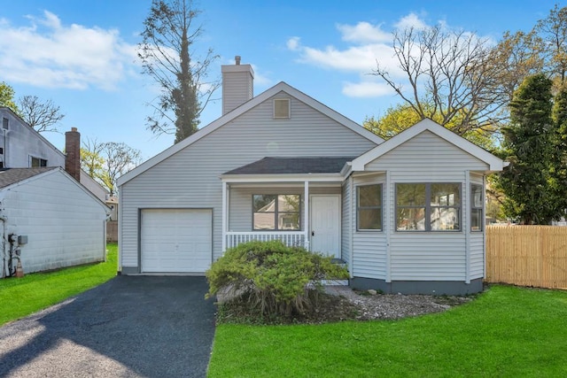 view of front of property with aphalt driveway, a shingled roof, a front yard, fence, and a garage