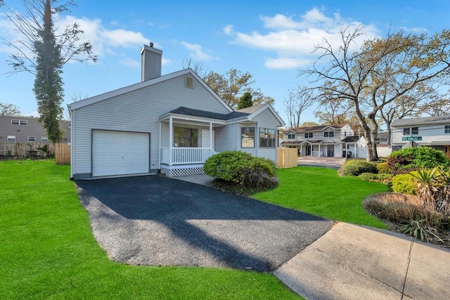 view of front facade with a front yard, driveway, a garage, and a chimney