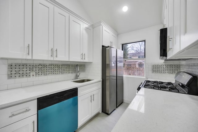 kitchen with a sink, white cabinetry, gas range oven, dishwasher, and freestanding refrigerator