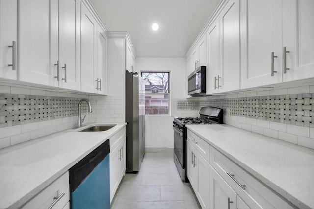 kitchen with appliances with stainless steel finishes, white cabinetry, backsplash, and a sink
