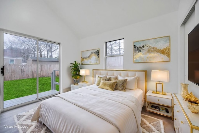 bedroom featuring lofted ceiling, wood finished floors, access to exterior, and multiple windows