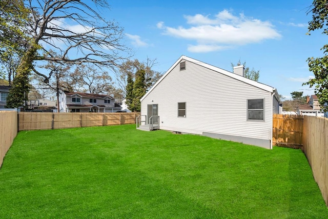 rear view of house with a yard, a fenced backyard, and a chimney