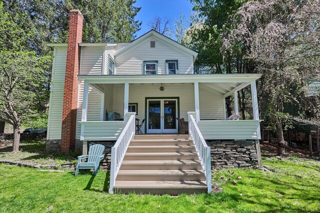 view of front of property with a front lawn, stairway, a chimney, french doors, and covered porch