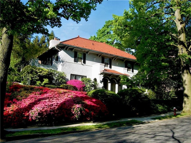 130 E Cedar St, Mount Vernon, NY 10552 - view of front facade featuring stucco siding, a chimney, a balcony, and a tile roof