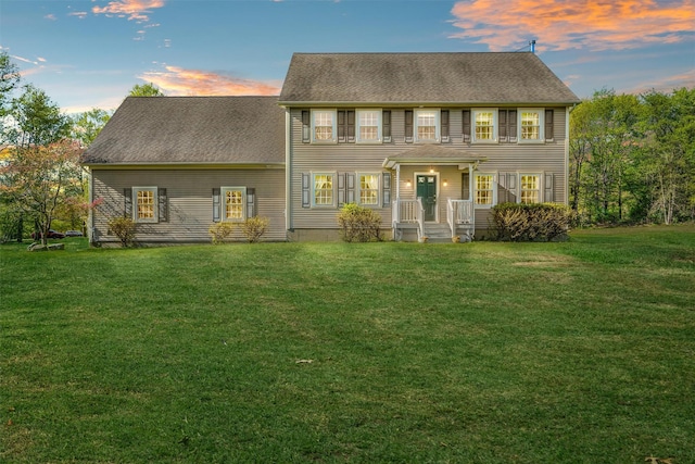 back of house at dusk featuring a yard