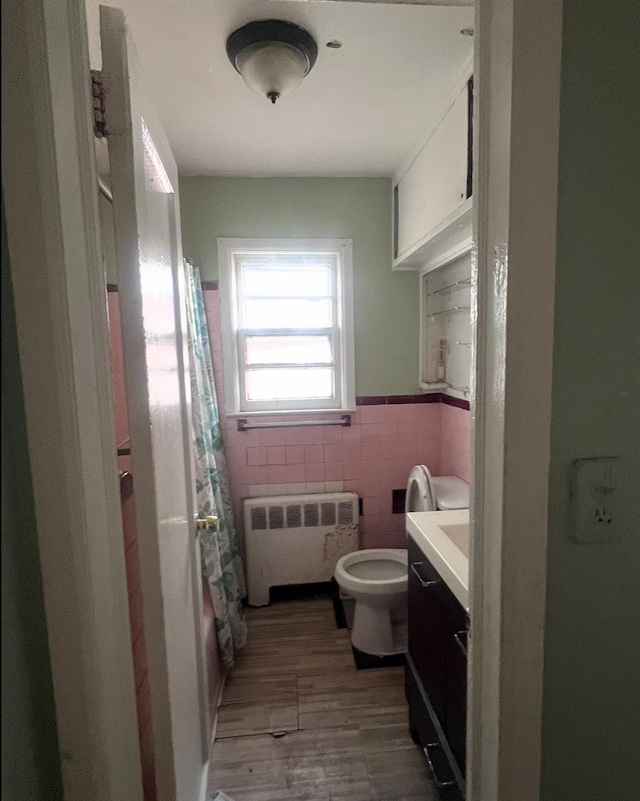 119 Broadfield Rd, Hempstead, NY 11550 - bathroom with radiator, tile walls, toilet, a wainscoted wall, and wood finished floors
