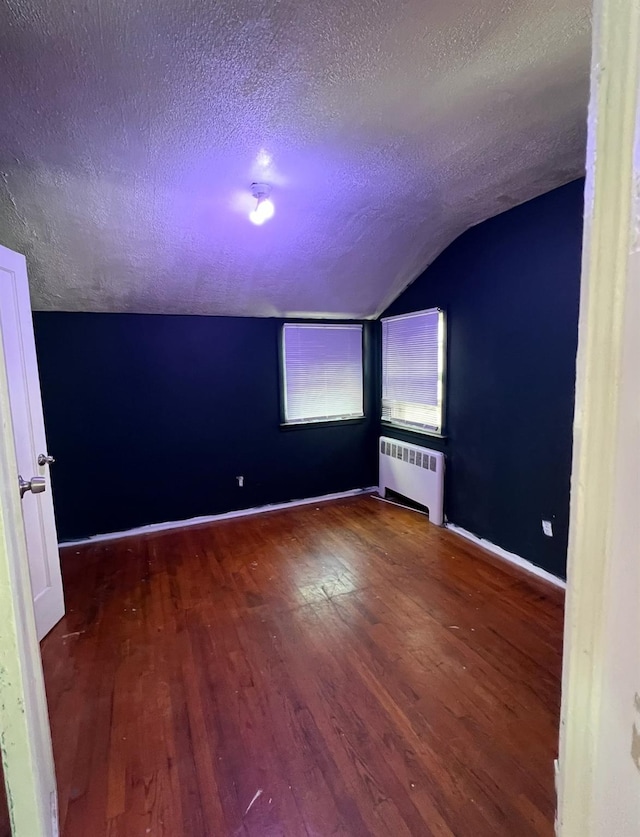 119 Broadfield Rd, Hempstead, NY 11550 - empty room with wood finished floors, radiator, baseboards, a textured ceiling, and lofted ceiling