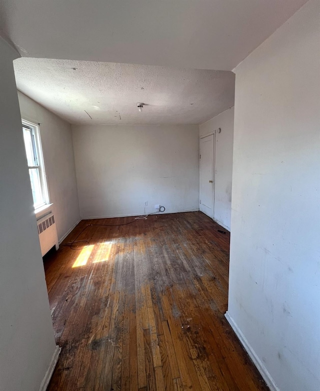 119 Broadfield Rd, Hempstead, NY 11550 - spare room featuring radiator, a textured ceiling, baseboards, and wood-type flooring