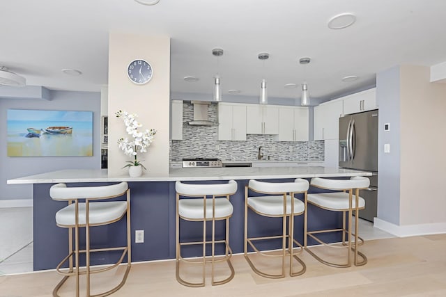 18 Shady Glen Ct Unit 302, New Rochelle, NY 10805 - kitchen featuring appliances with stainless steel finishes, tasteful backsplash, light countertops, a peninsula, and wall chimney exhaust hood