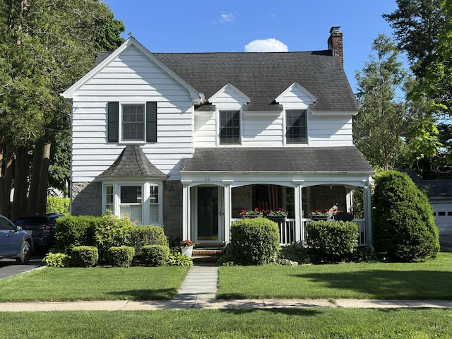 view of front of property with a front lawn, stone siding, covered porch, and a chimney