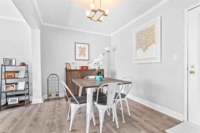 dining space featuring light wood-style floors, baseboards, an inviting chandelier, and ornamental molding