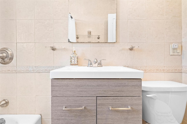 full bath with vanity, toilet, tile walls, a bath, and tasteful backsplash
