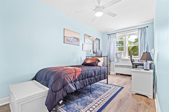bedroom featuring radiator, baseboards, a ceiling fan, and wood finished floors