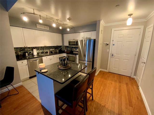 kitchen with crown molding, a sink, stainless steel appliances, white cabinetry, and decorative backsplash