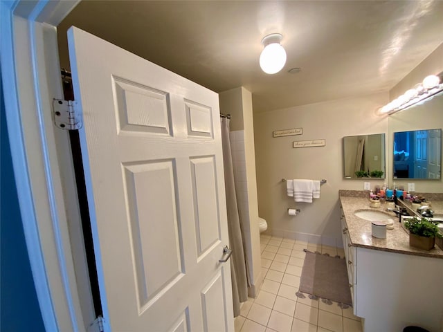 bathroom featuring vanity, baseboards, tile patterned floors, and toilet