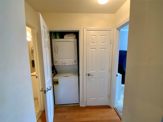 laundry room with stacked washer / drying machine, laundry area, and light wood-type flooring