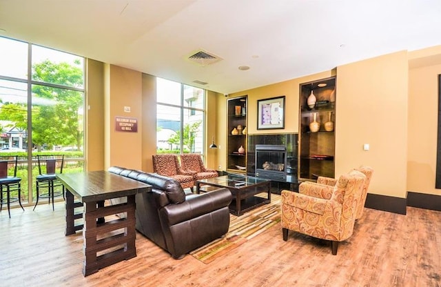 living room featuring wood finished floors, a tile fireplace, expansive windows, and visible vents