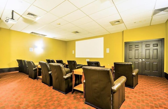 carpeted home theater with visible vents and a drop ceiling