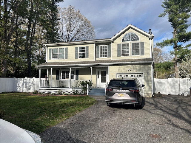 colonial inspired home featuring fence, a porch, aphalt driveway, and an attached garage