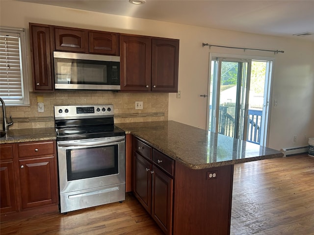 kitchen with a peninsula, appliances with stainless steel finishes, decorative backsplash, and visible vents