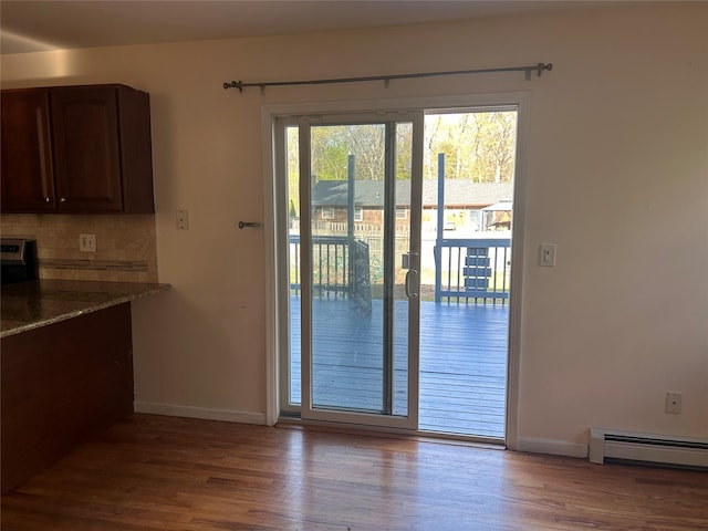doorway to outside with a baseboard radiator, wood finished floors, and baseboards