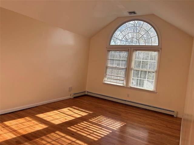 empty room with lofted ceiling, visible vents, baseboard heating, baseboards, and wood finished floors