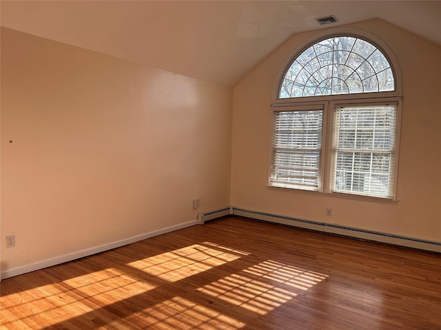 empty room featuring visible vents, vaulted ceiling, wood finished floors, and a baseboard radiator