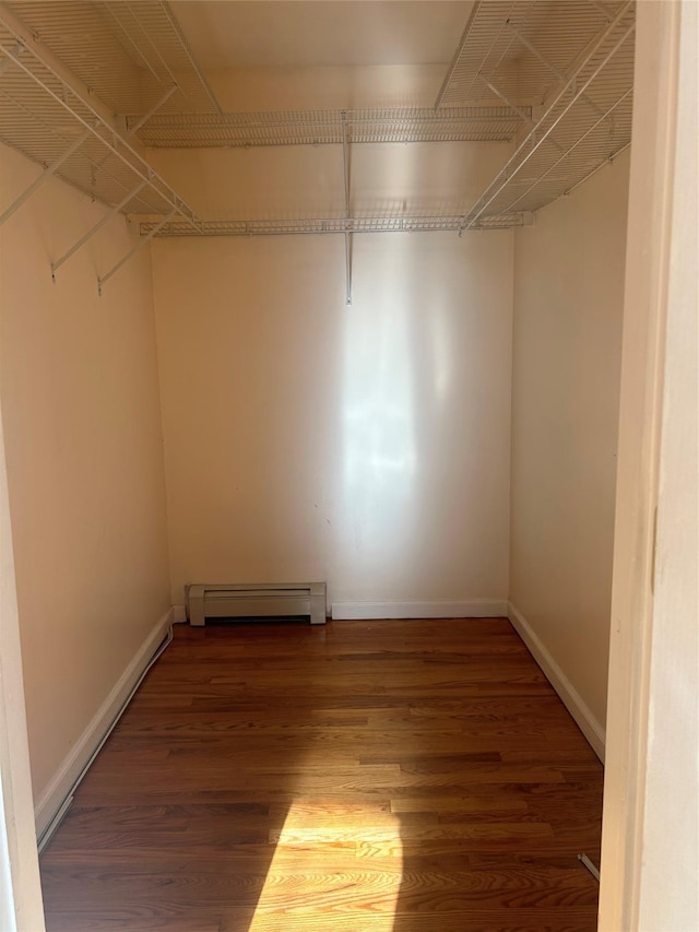 walk in closet with a baseboard radiator and wood finished floors