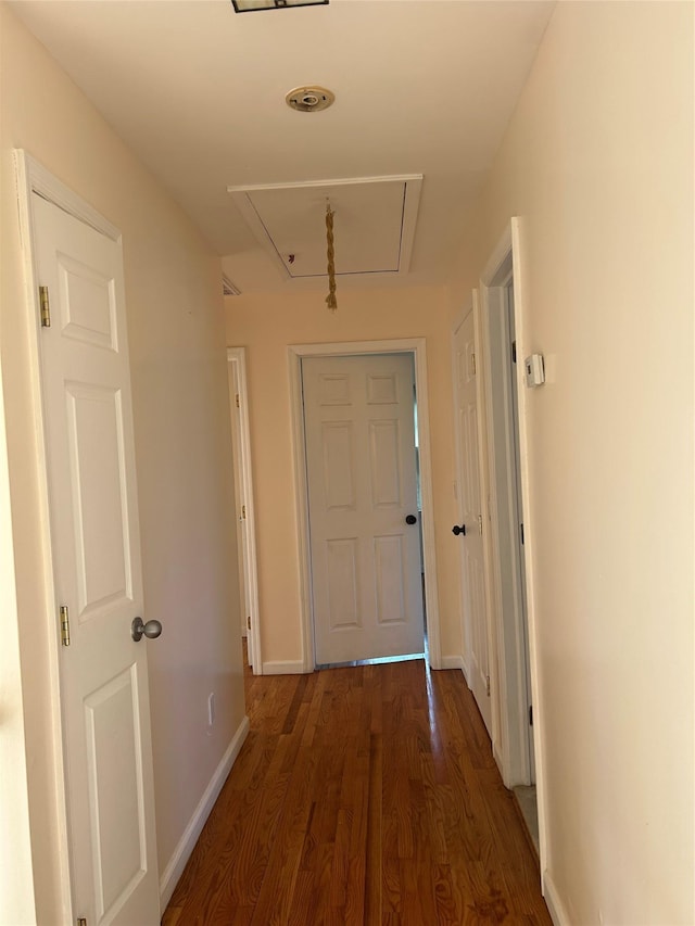 hall featuring attic access, wood finished floors, and baseboards