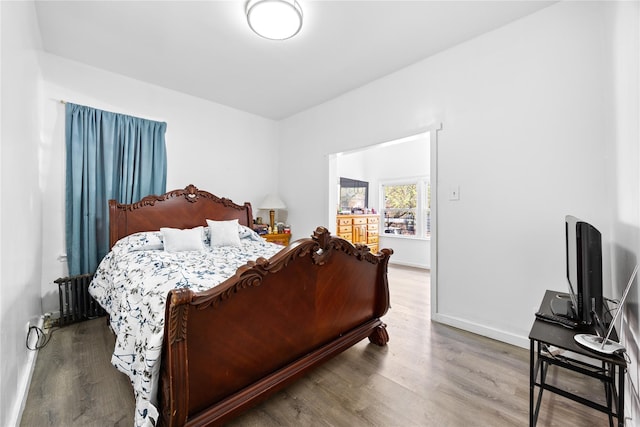 bedroom with baseboards, radiator heating unit, and wood finished floors