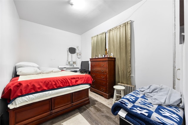 bedroom featuring radiator and wood finished floors