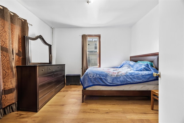 bedroom featuring radiator heating unit and light wood-type flooring