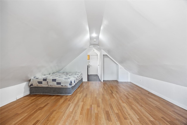unfurnished bedroom with baseboards, light wood-style floors, and vaulted ceiling